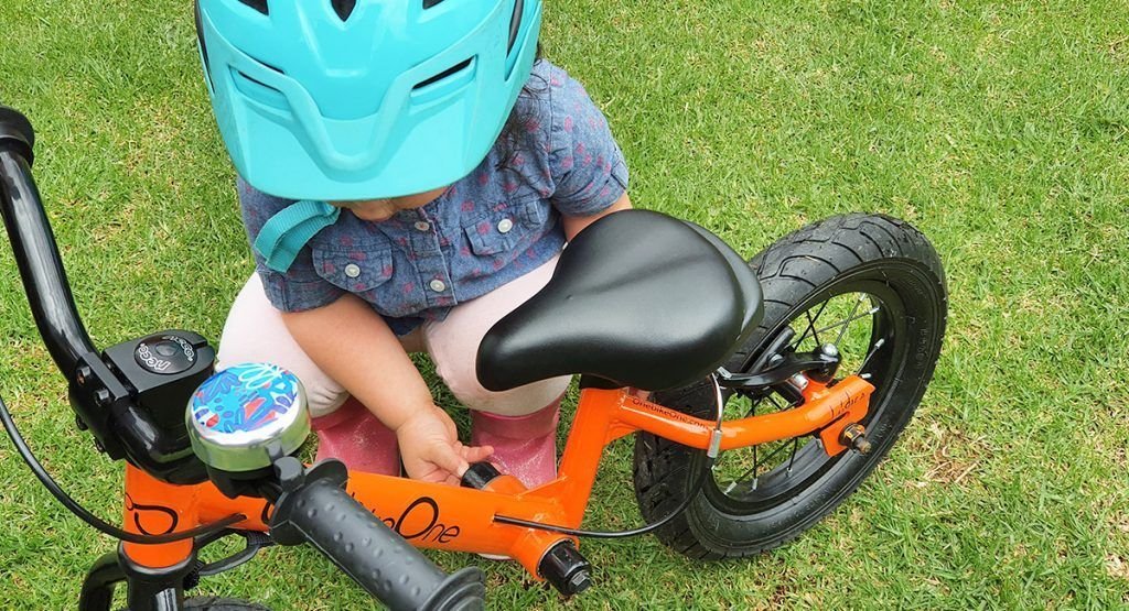 Niña ajustando bicicleta de aprendizaje
